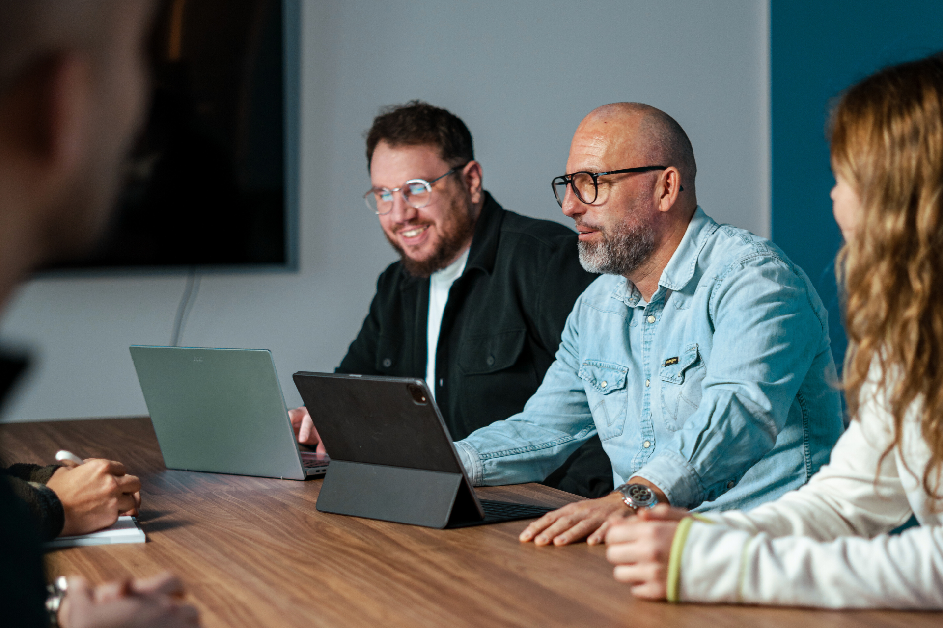 Man sieht den Gründer von Semtrix und Mitarbeiter am Besprechungstisch im Büro sitzen und auf Tablets schauen. Dabei wird gelacht.